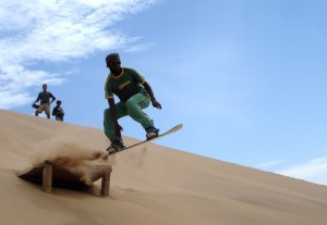 Von einer Sprungschanze in der Namib-Wüste hebt Sandboarding-Lehrer Raymond Inichab hebt ab.