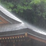 Hart schlägt der kurze Regenschauer auf das Dach eines Tempelgebäudes